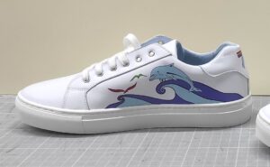 deportiva de mujer de piel con detalles estampados con motivos de delfines. Vista lateral